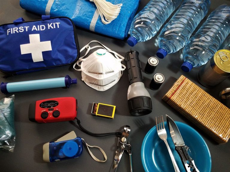 Flat lay of emergency survival kit items with first aid supplies and water bottles