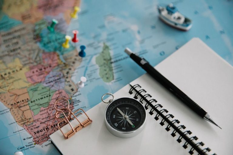 Map, compass, notebook and pen laid out for planning