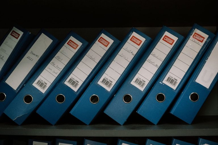 Neatly labeled blue binders organized on a shelf